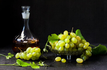 Fresh ripe grapes and decanter with grape juice on black background