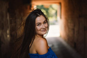 Fototapeta premium Portrait happy young woman wearing blue dress laughing looking at camera standing on street. Urban background