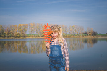 Fototapeta na wymiar cute child and blue pond in sunny autumn day in countryside