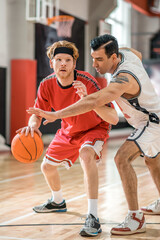 Fototapeta premium Two young men playing basketball and looking excited