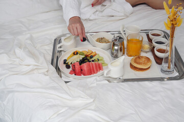Obraz na płótnie Canvas Breakfast tray in bed in luxury resort. Breakfast in bed with fruits, pancakes, cereals, coffee and juice on a tray.