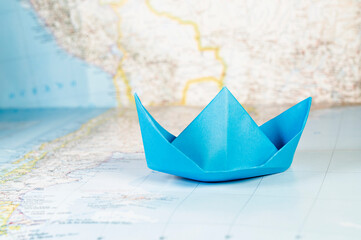 Blue paper boat on map