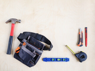 Building bag for belt and some working instruments tools on plywood of surface with copy space