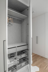 New empty modern closet wardrobe shelves by grey finish  material and opened doors. Closet with hangers and rail rack
