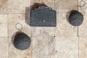 Bamboo charcoal bathroom accessories - konjac bamboo charcoal black sponges and handmade black charcoal soap on earth toned stone tales top view