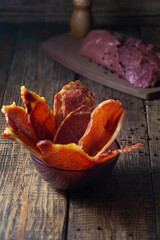 Ready-made jerky is laid out on a plate. Wooden brown background, vertical orientation.