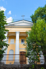 Old German church among the branches of green trees with closed gates - Russia, Novosoratovka, St. Petersburg, August 2021