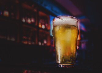 glass of light beer stands on bar counter in a bar or pub