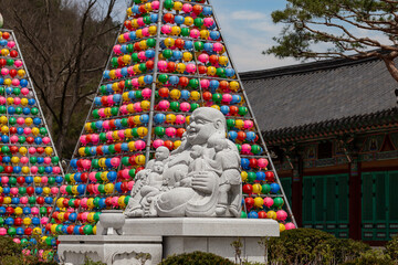 Buddha statue in a buddhist temple Songgwangsa, colorful lantern towers on background, South Korea