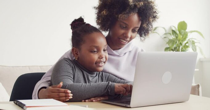 African mom helping kid with homework on laptop