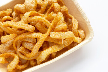 Fried crispy pork rinds in plate on white background.