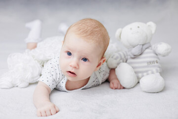 New born child, little girl crawling and playing with toys.