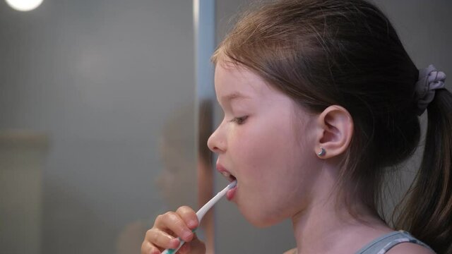 little girl brushing her teeth in the bathroom