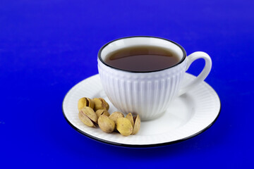 Pistachios in a white plate on a blue background