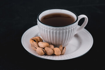 Pistachios in a white plate on a black background