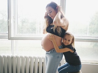little daughter hugs pregnant mom