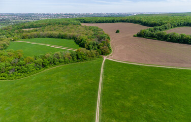 Green summer rural landscape panorama with pasture, dirt fields, road lines and forest around. Aerial countryside on sunny day