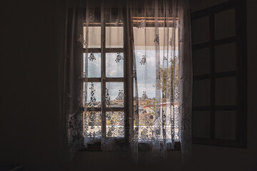 View outside from Greek traditional house opened window with curtains on sunny summer Aegean sea coast village. Country house near Athens, Greece