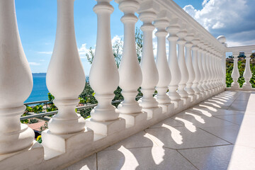 Traditional white balusters close-up. Greek architecture elements of terrace. View through balcony on clear blue Aegean sea coast. Summer country house near Athens, Greece