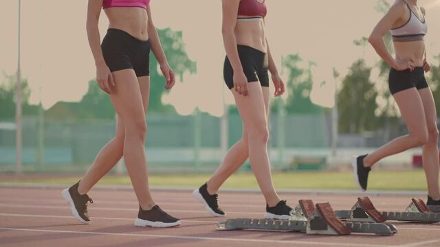 A group of women at the track and field competition warm up and prepare for the race. Concentrating on the start line at the stadium
