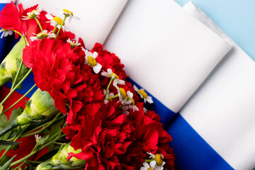 Red carnations on the background of the flag of Russia. White, blue and red colors. Greeting card. 22 August Day of the State Flag of the Russian Federation. June 12 is the Independence Day of Russia.
