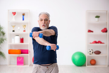 Fototapeta na wymiar Old man doing sport exercises indoors