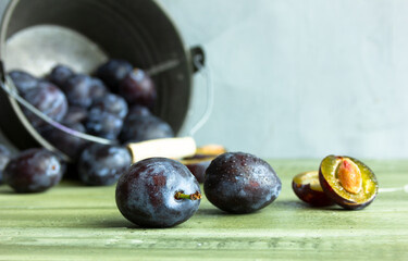 blue plums on a wood background, fresh fruits, summer, autumn, fruits in the bucket, seasonal,...
