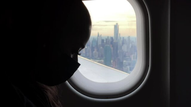 silhouette of passenger flying window seat view of Manhattan New York City skyscrapers buildings interior airplane NYC