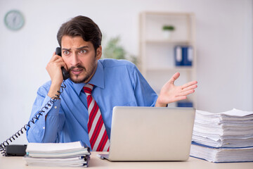 Fototapeta premium Young male employee unhappy with excessive work in the office