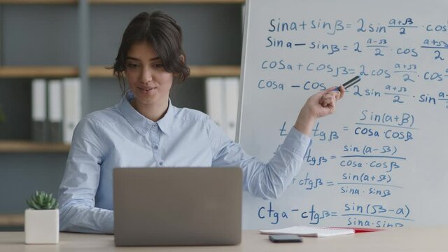 Online tutoring concept. Young lady practicing e-learning, explaining math formulas on whiteboard to student