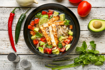 Composition with tasty Sopa de Lima soup on light wooden background