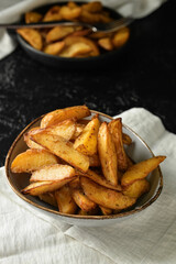 Bowl with tasty baked potato on dark background
