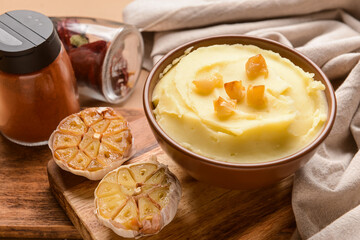 Bowl of tasty mashed potatoes with garlic on table