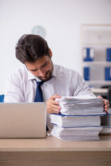 Young male employee unhappy with excessive work in the office