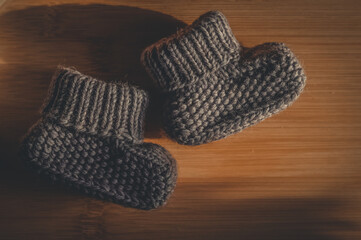 A pair of gray booties for a small child. Early morning, light from the window.