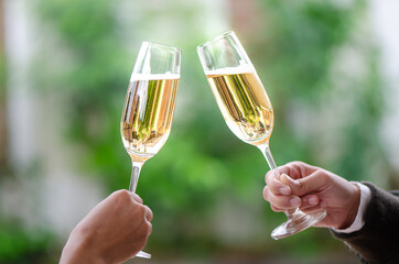 Fototapeta premium two person holding two glasses of white wine at a celebration dinner