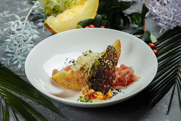 baked melon with parmesan and jamon on a white plate