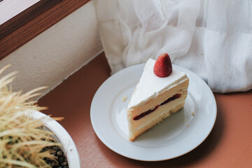 Strawberry and cream sponge cake on white plate. Dessert. On a wooden background. Top view. Free space for your text.