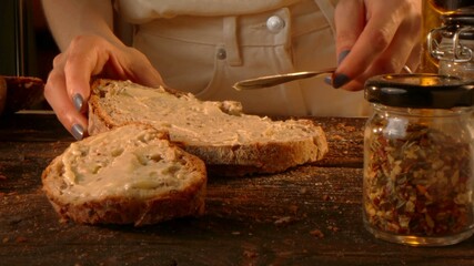 Hands of a woman who is buttering toasts