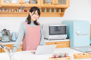 キッチンでパソコンを見る女性