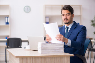 Fototapeta premium Young male employee and too much work in the office