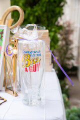 beer glass that says someone get this beer a guy, wrapped in cellophane and a purple ribbon