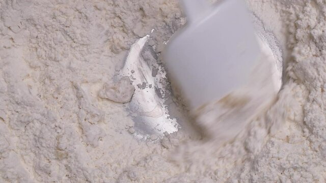 Female hands mixing flour and eggs with a ladle prepared for homemade pizza dough or bread. Cooking process.