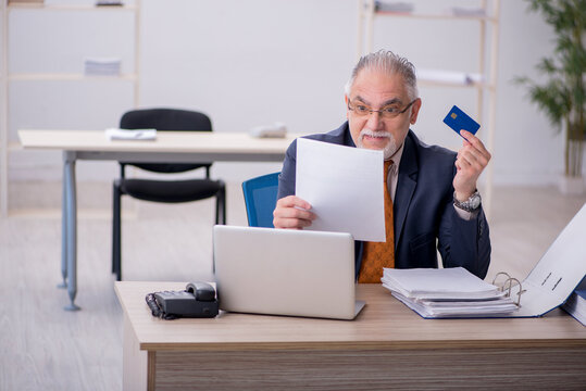 Old male employee holding credit card in the office