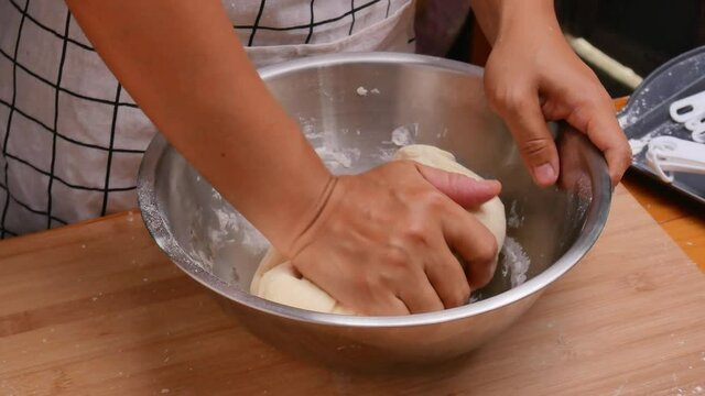 Female hands mixing flour, fresh milk and chicken eggs prepares dough for homemade pizza. Cooking process.