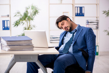 Young male employee and too much work in the office