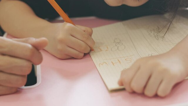 Close up 4K of asian mom is teaching her adorable child daughter focusing on hands writing for homework and homeschool education shows concept of parental love and togetherness who alway support. 