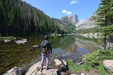 Young woman enjoys view of Dream Lake from Emerald Lake Trail in Rocky Mountain National Park,...