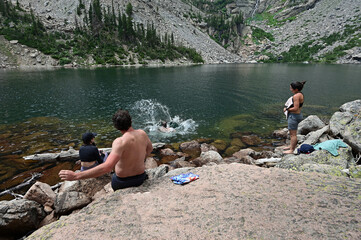 Young hikers relax and swim in Emerald Lake in Rocky Mountain National Park, Colorado on sunny...