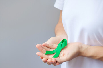 Hand holding green Ribbon for Liver, Gallbladders, bile duct, cervical, kidney Cancer and Lymphoma...